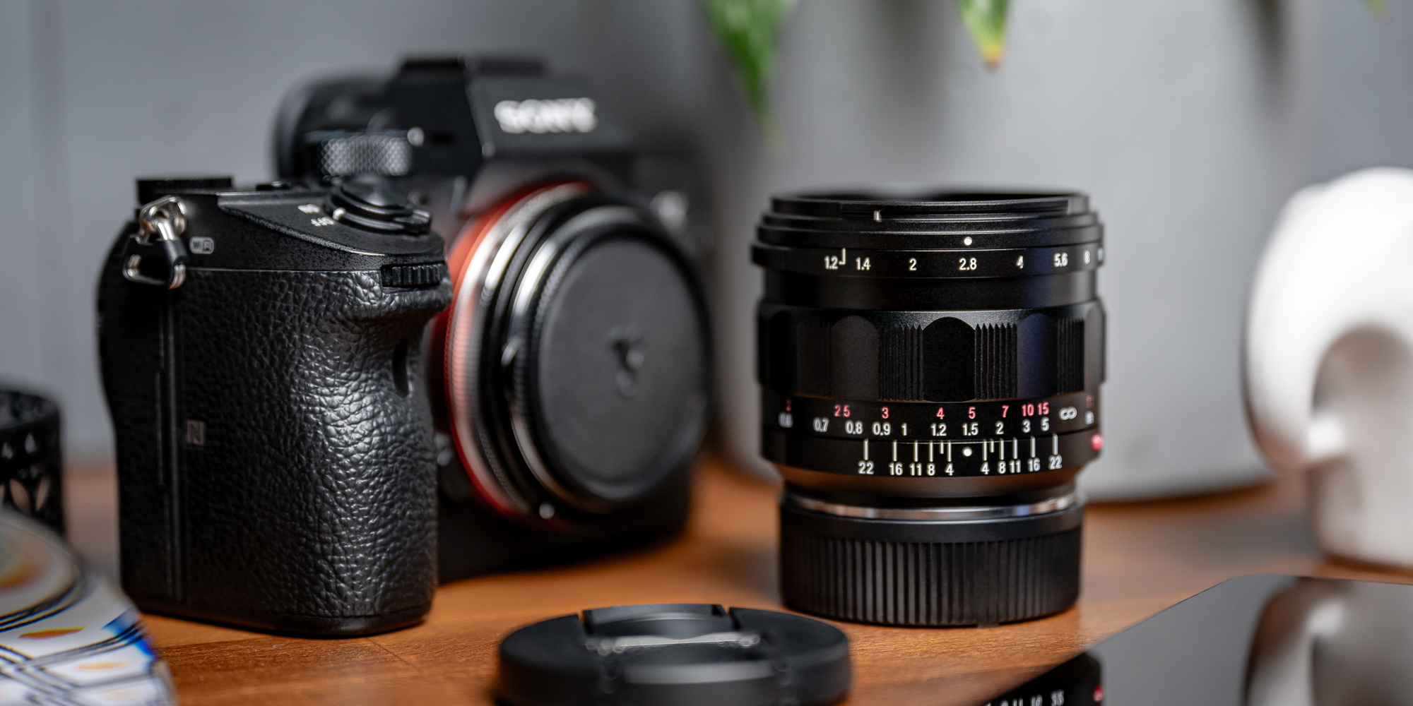 Obiektyw Voigtlander Nokton IV 35 mm f/1,2 do Leica M na biurku pośród różnych przedmiotów